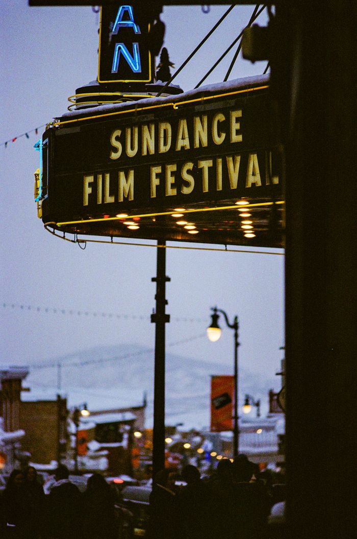 Sundance Film Festival marquee on a snowy street with people and lights in the background.