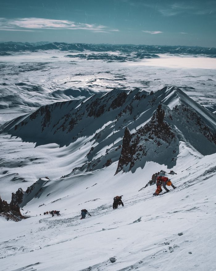 Group of climbers ascending a snowy mountain in winter, showcasing adventure and breathtaking scenery.