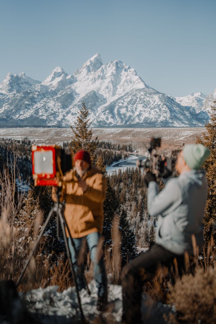 Two photographers using tripods capture stunning winter mountain scenery.