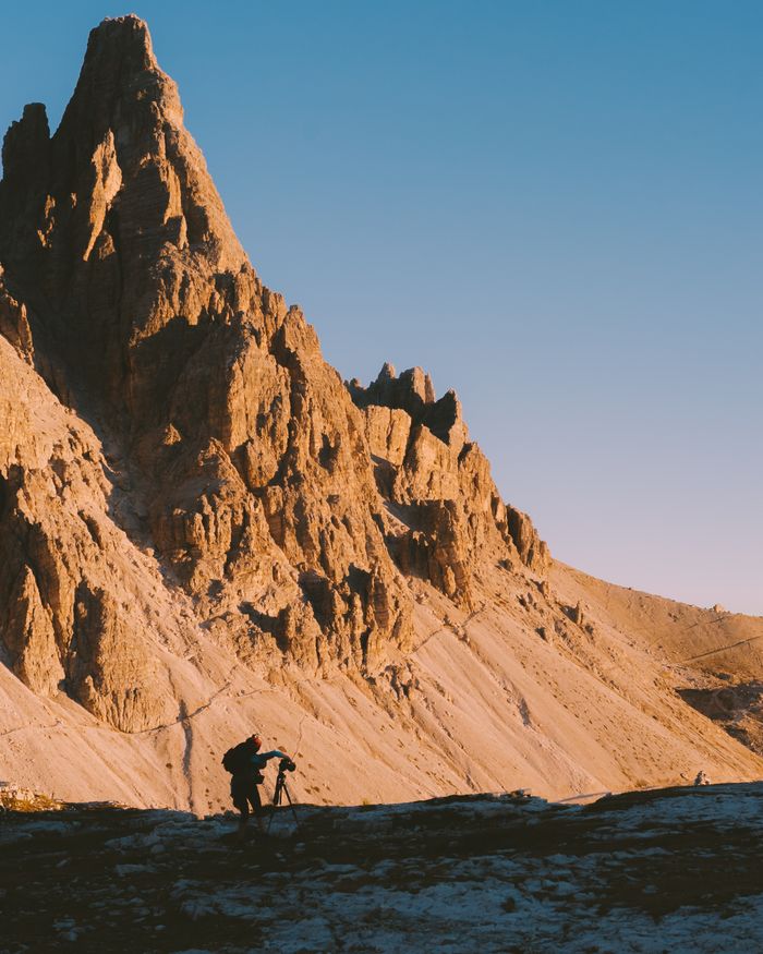 A dramatic mountain landscape in Veneto, Italy, with a photographer capturing the scene.